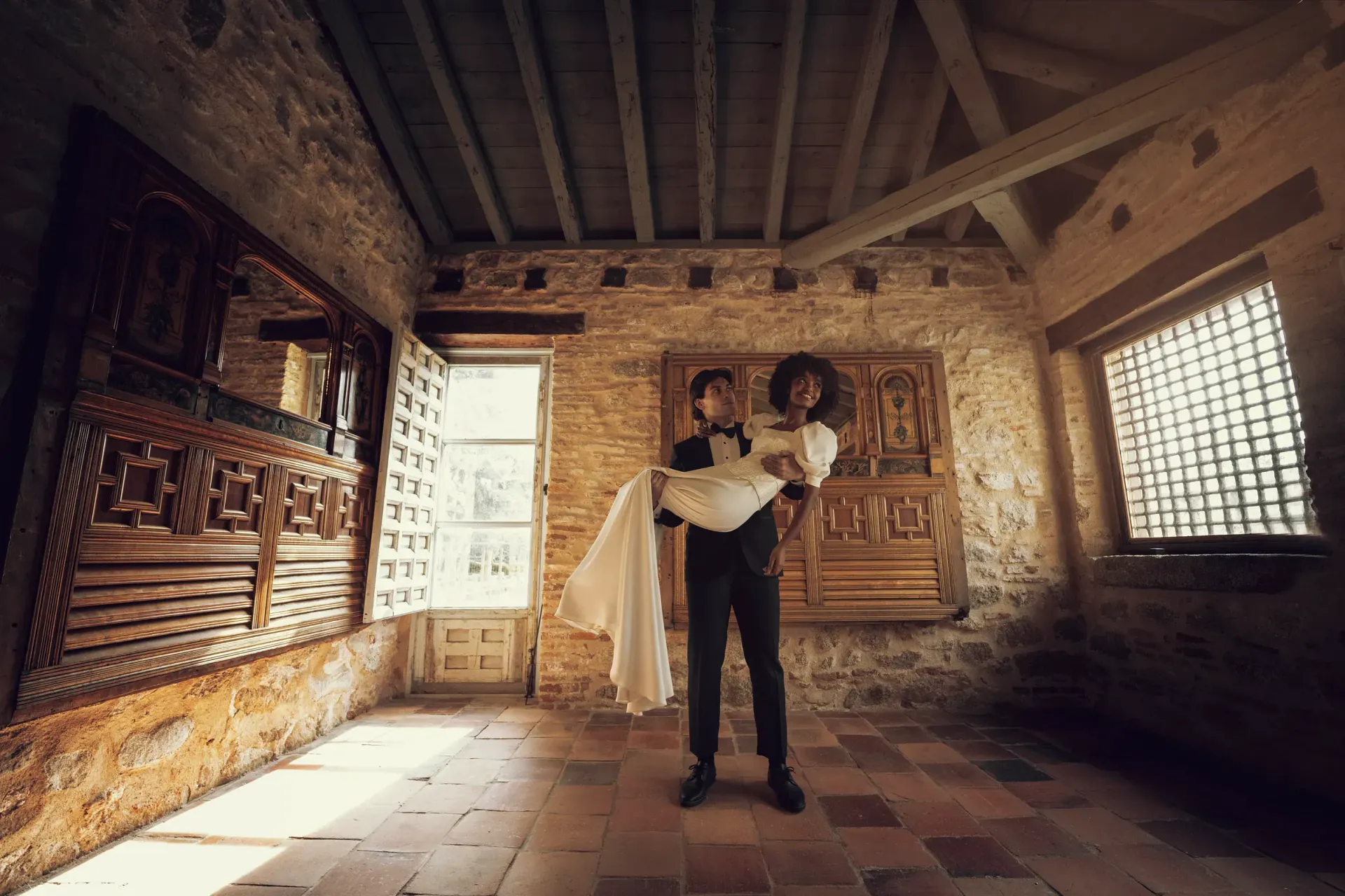 Un hombre sostiene a una mujer en sus brazos en una habitación.