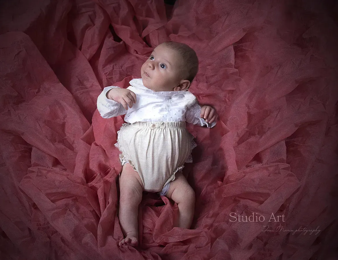Un bebé está acostado sobre una manta rosa.