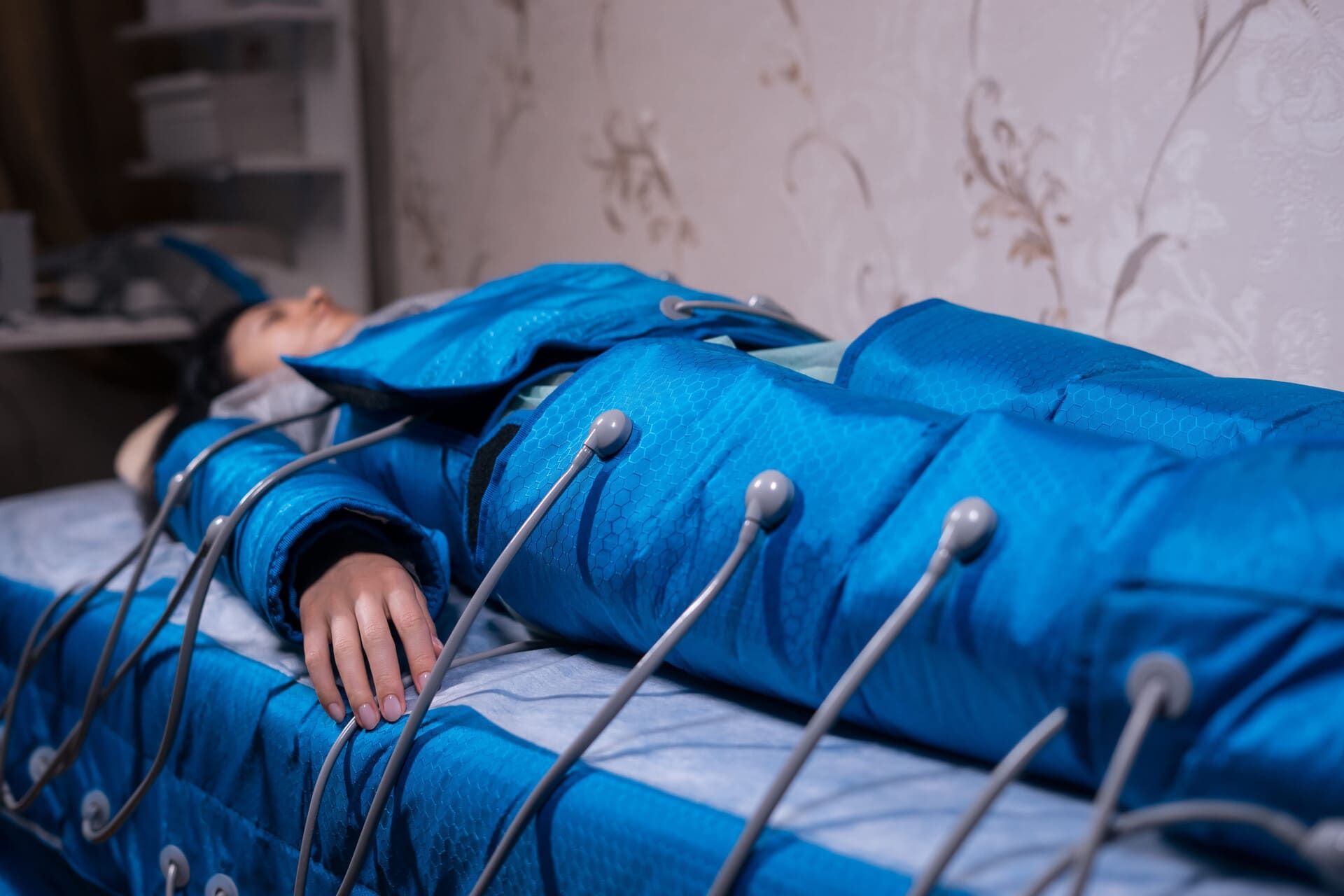 Una persona yace sobre una mesa bajo un dispositivo azul de terapia de electrochoque con sondas metálicas conectadas.