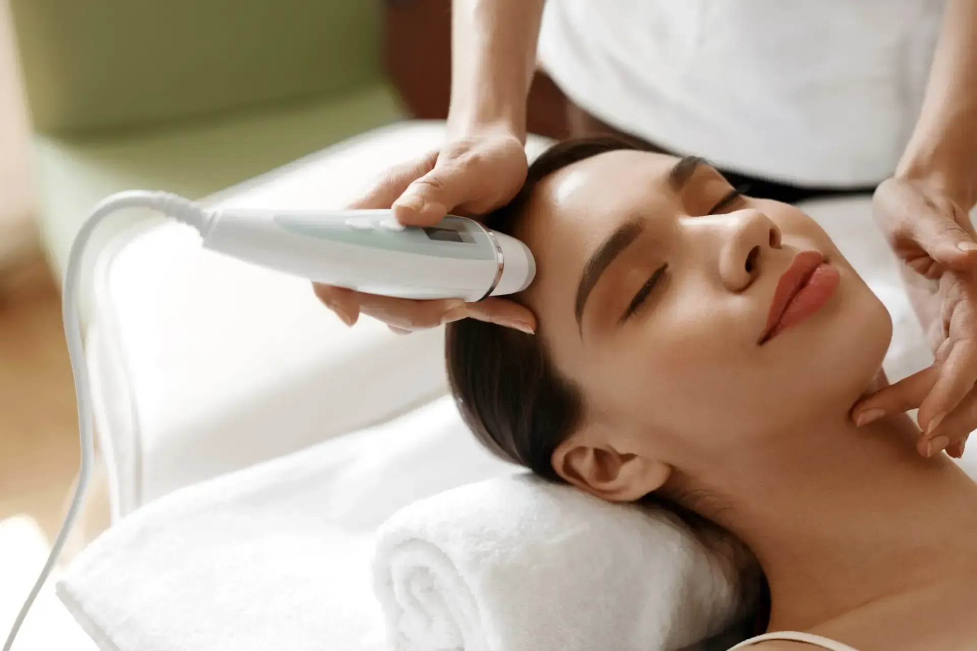 Durante un tratamiento de spa, un profesional utiliza un dispositivo cosmético manual en la frente de una persona.