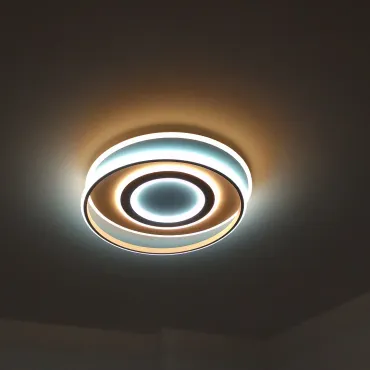 Luminaria de techo circular con múltiples anillos, que emite una suave luz blanca y cálida amarilla.