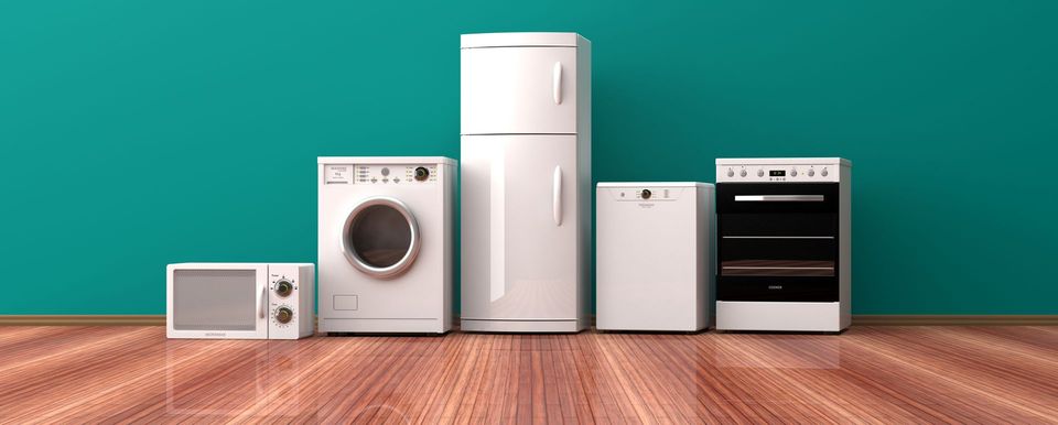 Une rangée d'appareils électroménagers blancs dans la cuisine, disposés sur un parquet contre un mur turquoise, comprenant un micro-ondes, un lave-linge, un réfrigérateur, un lave-vaisselle et un four.