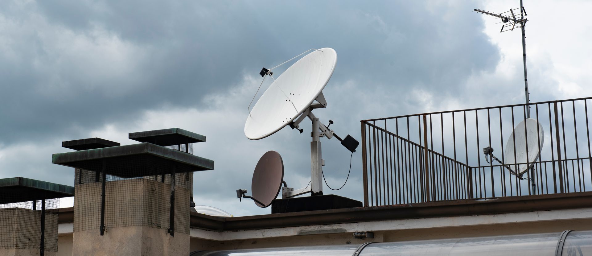 Toit avec des paraboles et des antennes paraboliques sur fond de ciel nuageux