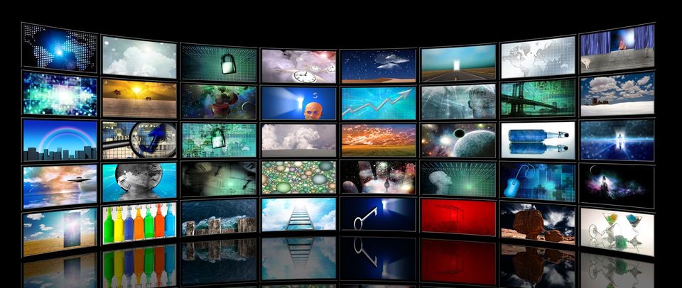 Un mur incurvé composé de nombreux écrans de télévision colorés diffusant des scènes et des paysages abstraits variés.