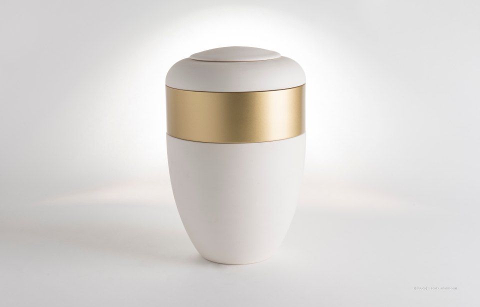 Weiße Einäscherungsurne mit Goldband.