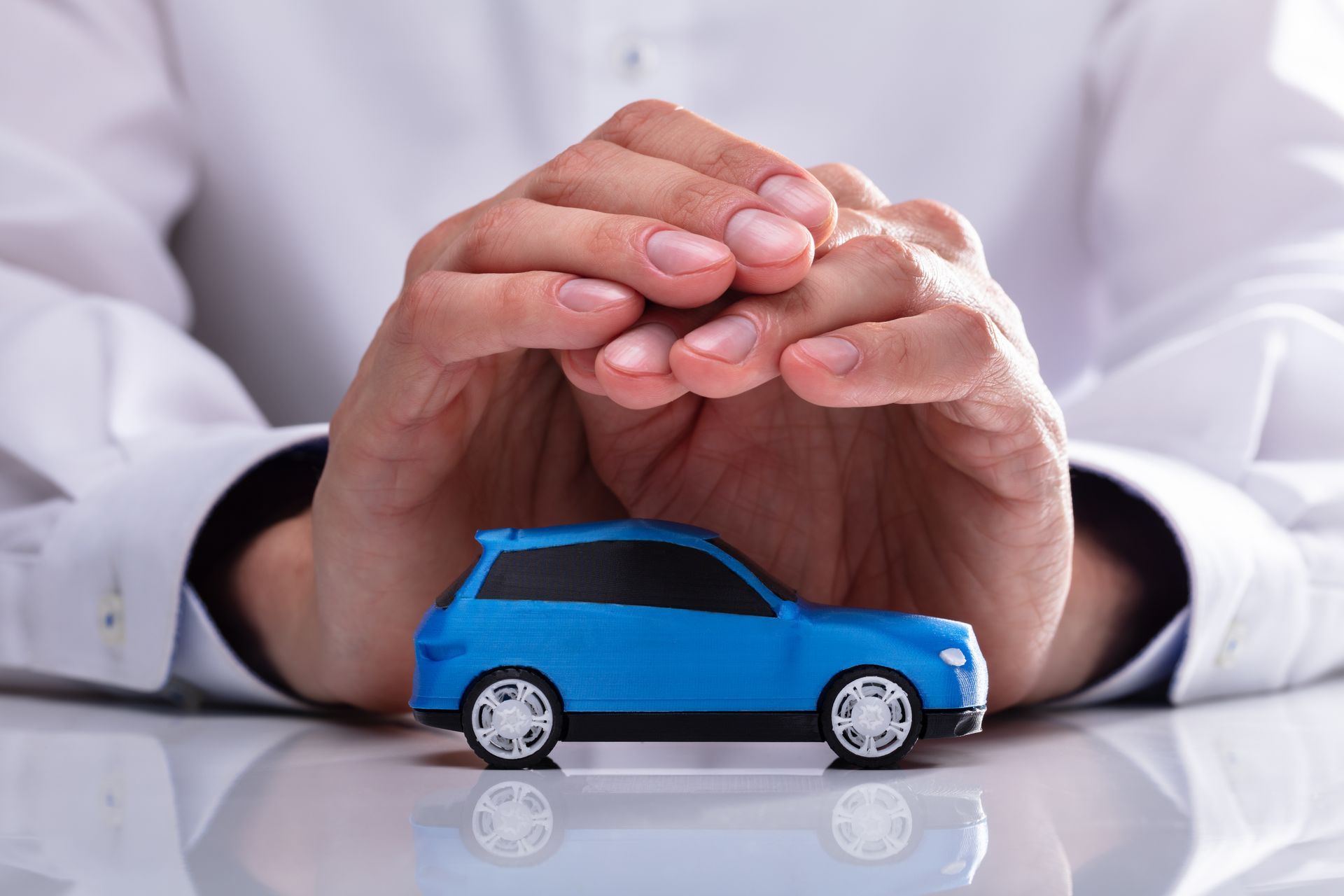 Main en protection au-dessus d'une voiture en jouet