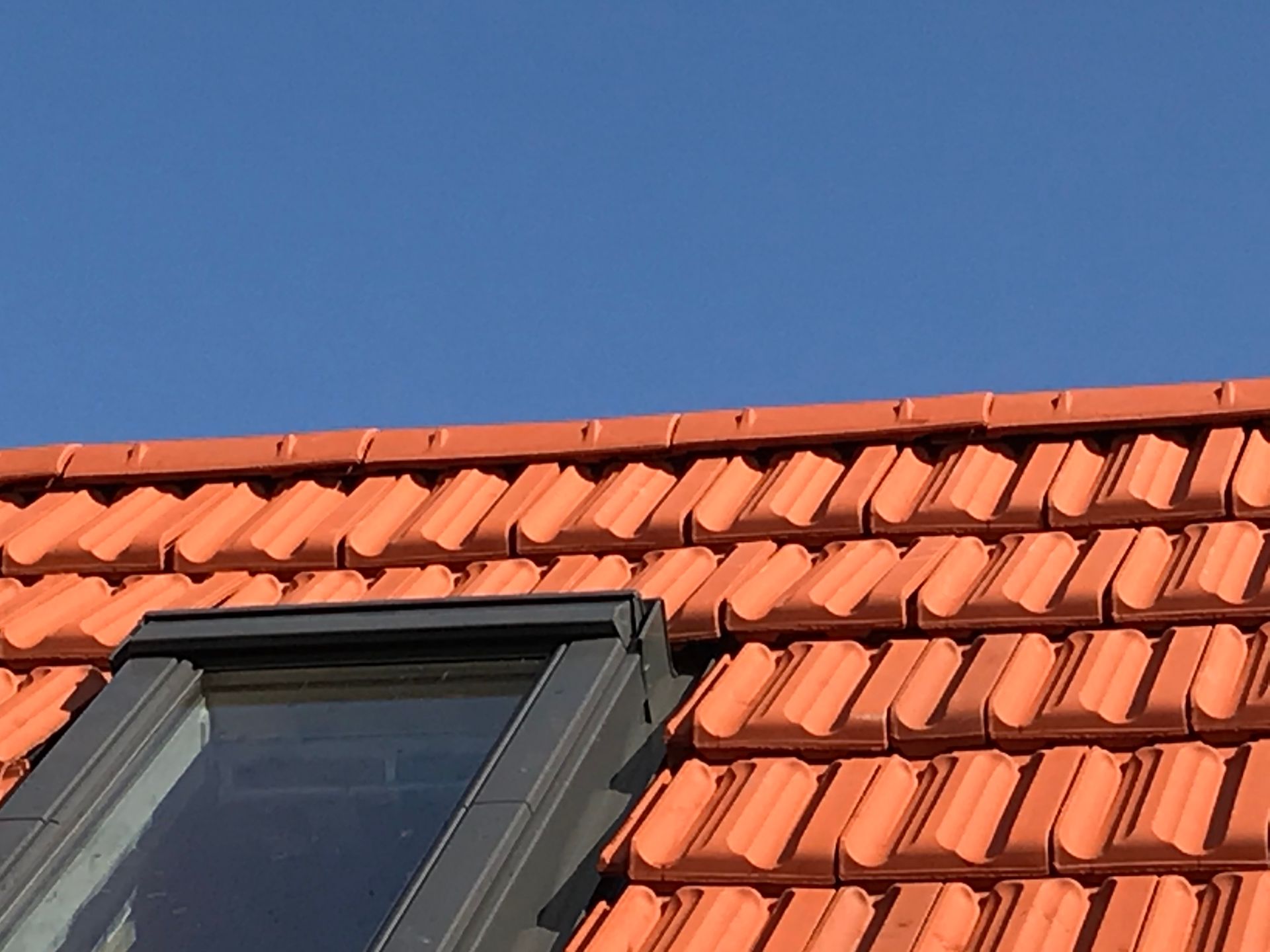 Rotes Ziegeldach mit Dachfenster – Dachsanierung.
