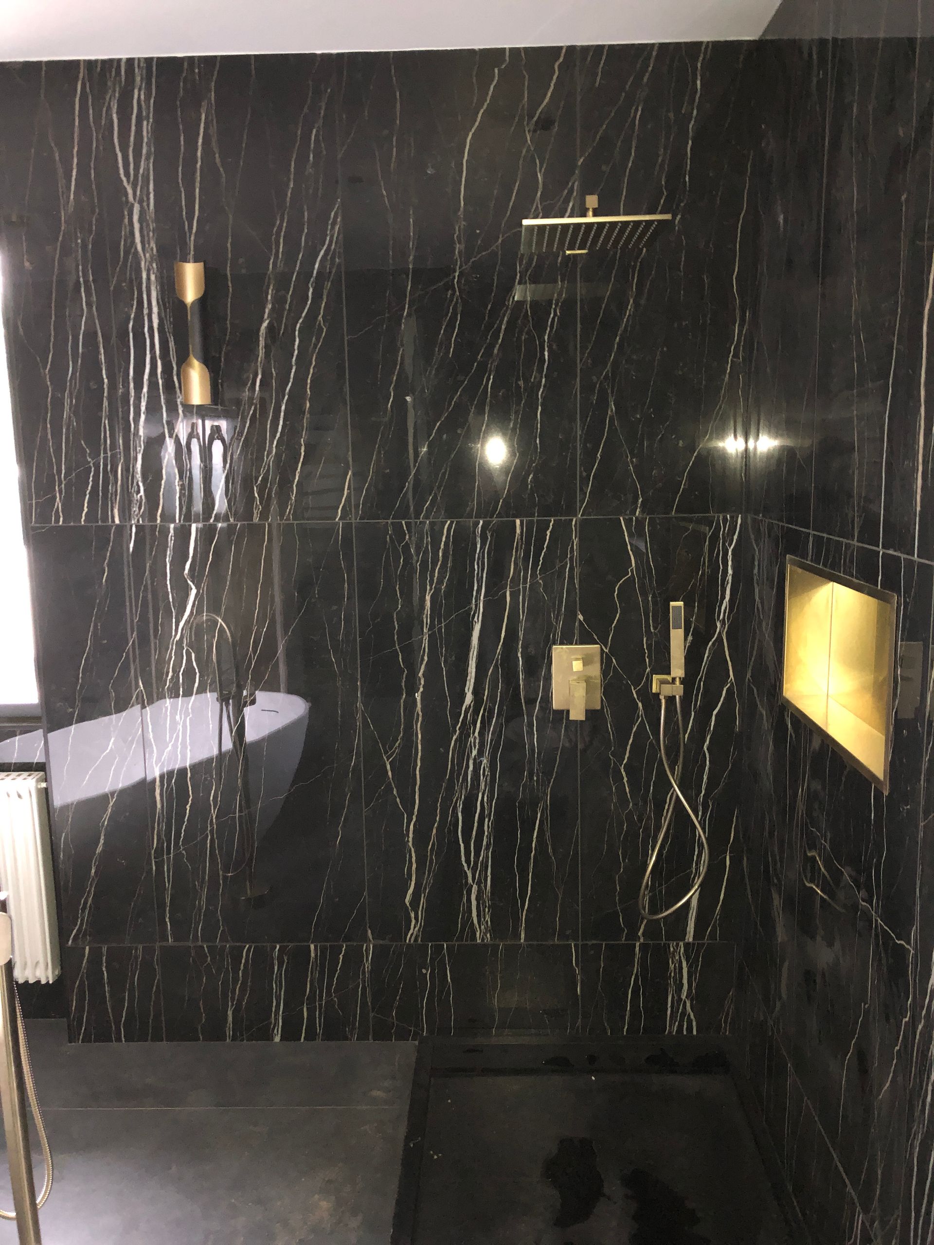 Pose de carreaux noirs avec des traits dorés sur les murs d'une salle de bains