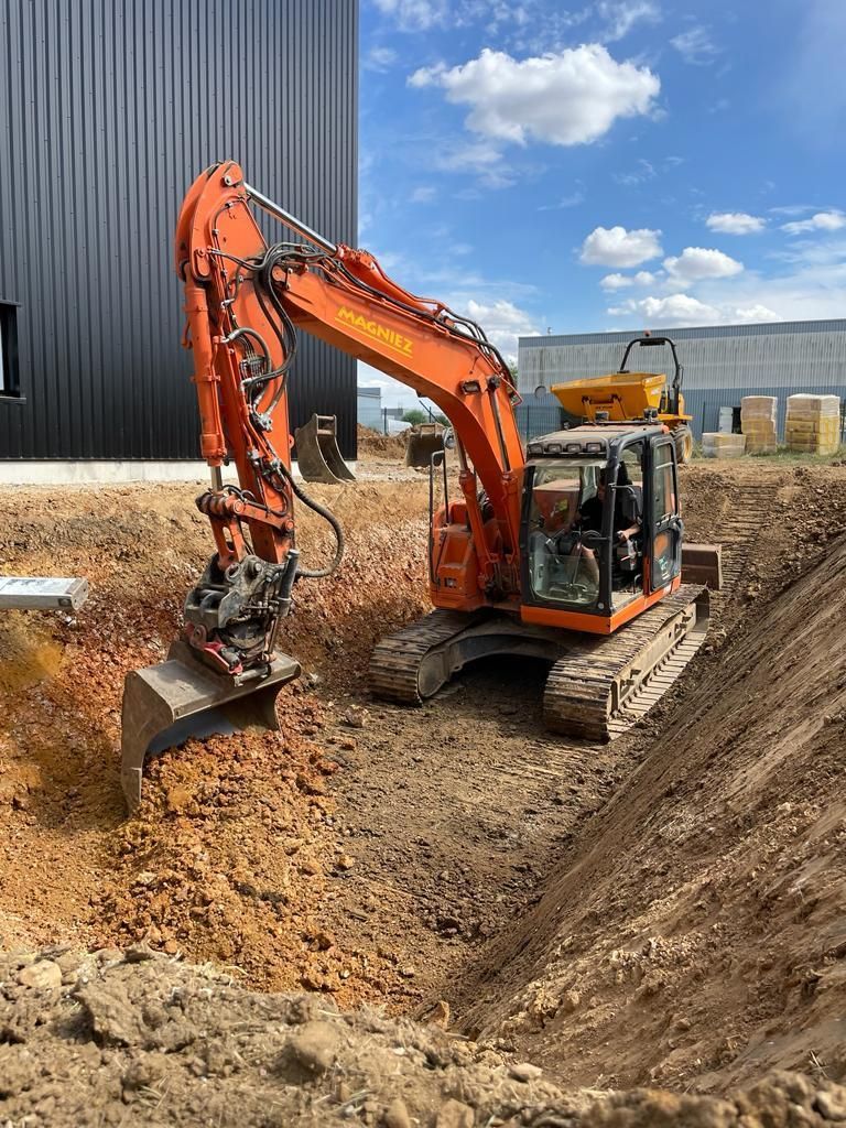 Un engin de chantier orange creusant dans de la terre