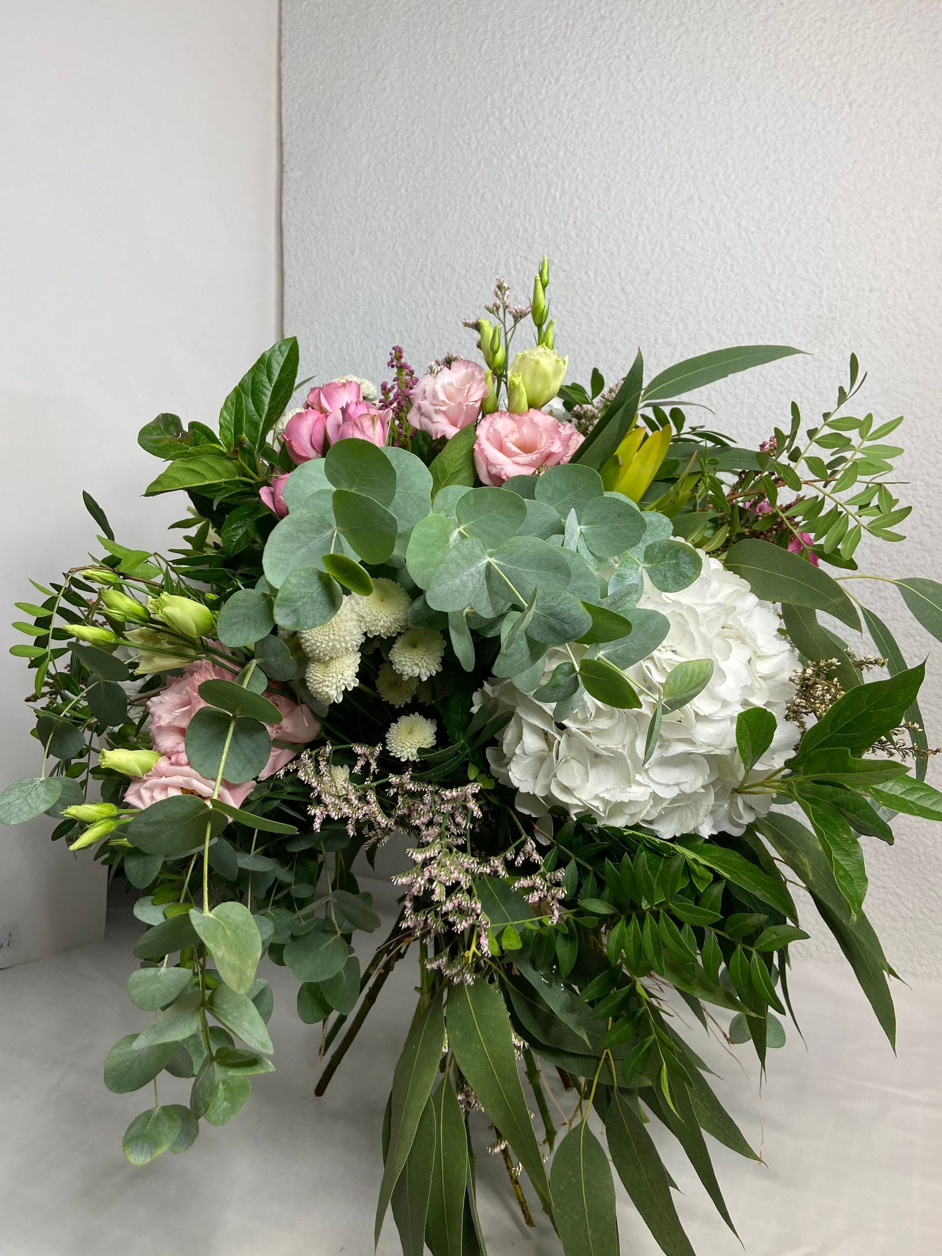 Un ramo de flores y hojas está sobre una mesa.