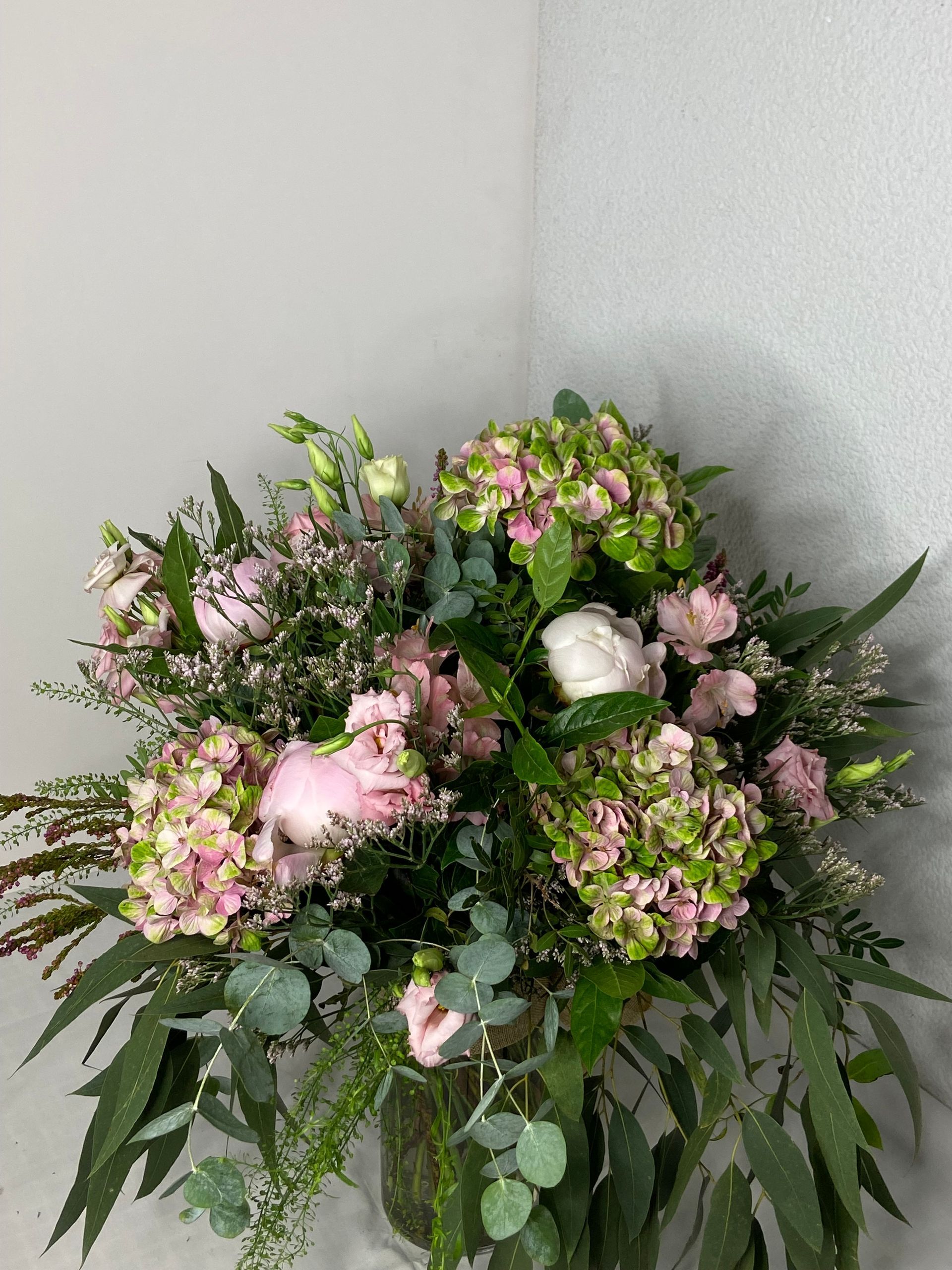Un jarrón lleno de flores rosas y verdes está sobre una mesa.