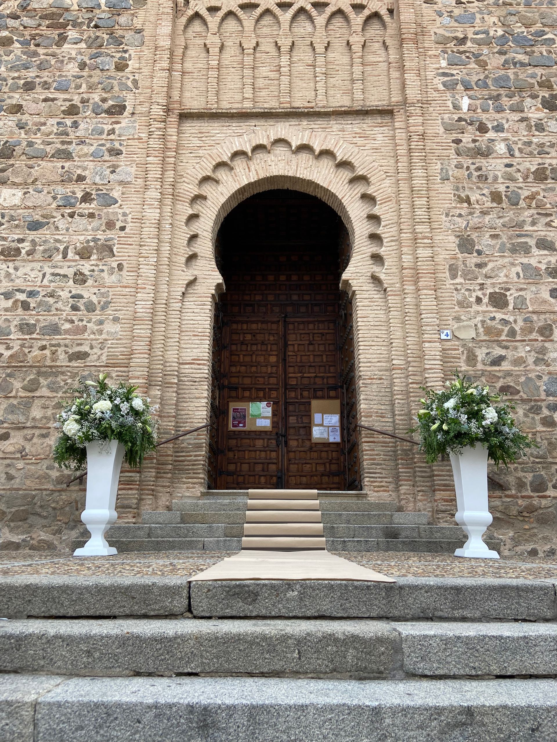 Una iglesia con dos jarrones con flores delante de ella.