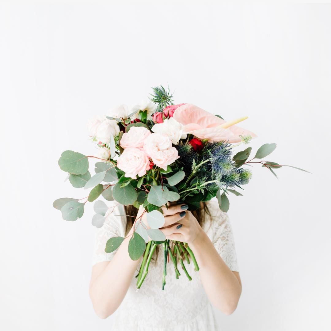 Una mujer sostiene un ramo de flores delante de su cara.