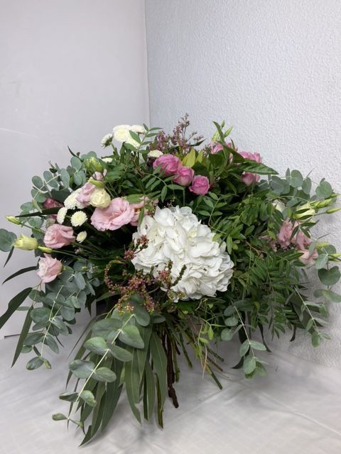 Un gran ramo de flores rosas y blancas está sobre una mesa.