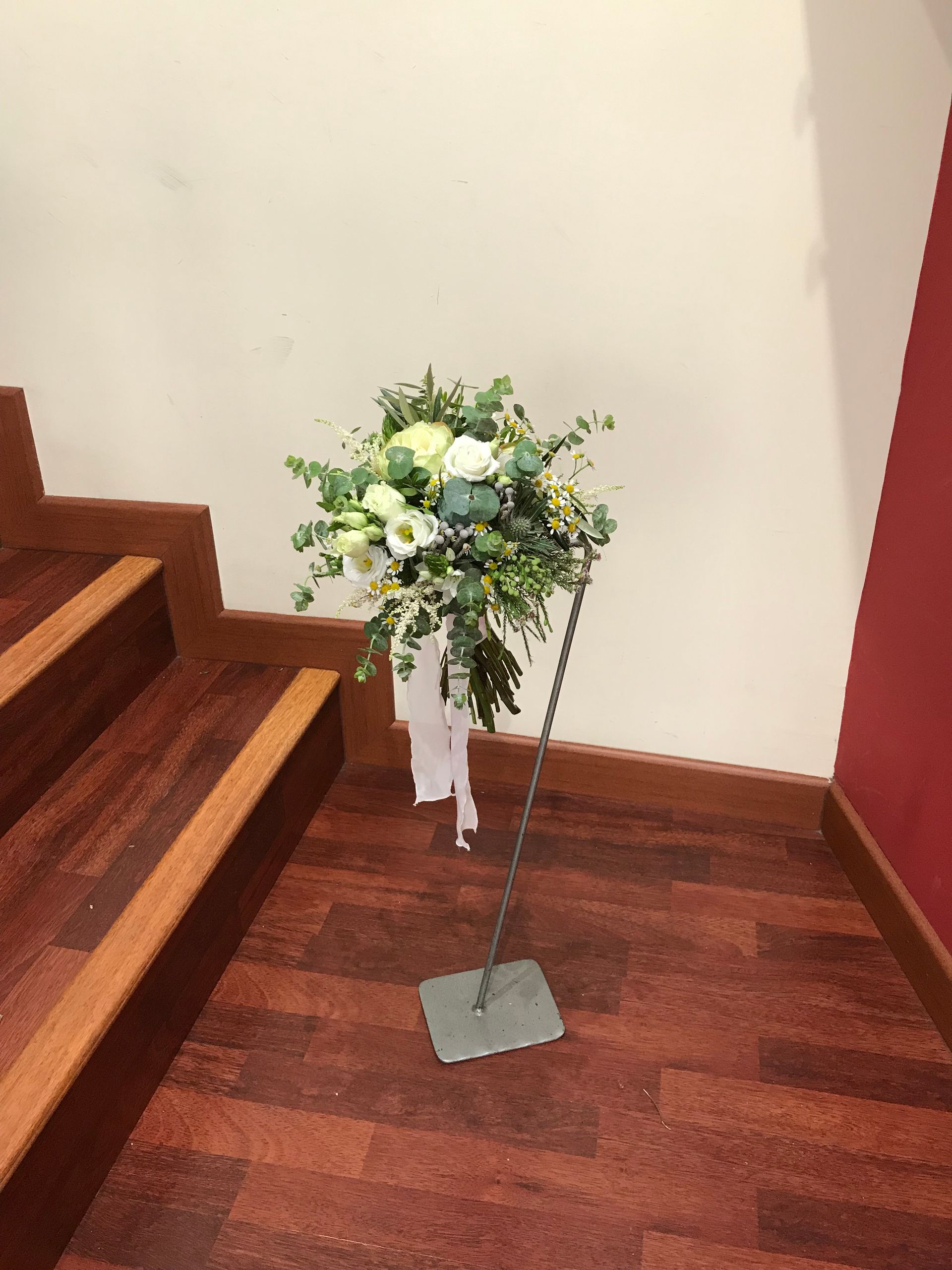 Un ramo de flores está sobre un suelo de madera al lado de unas escaleras.