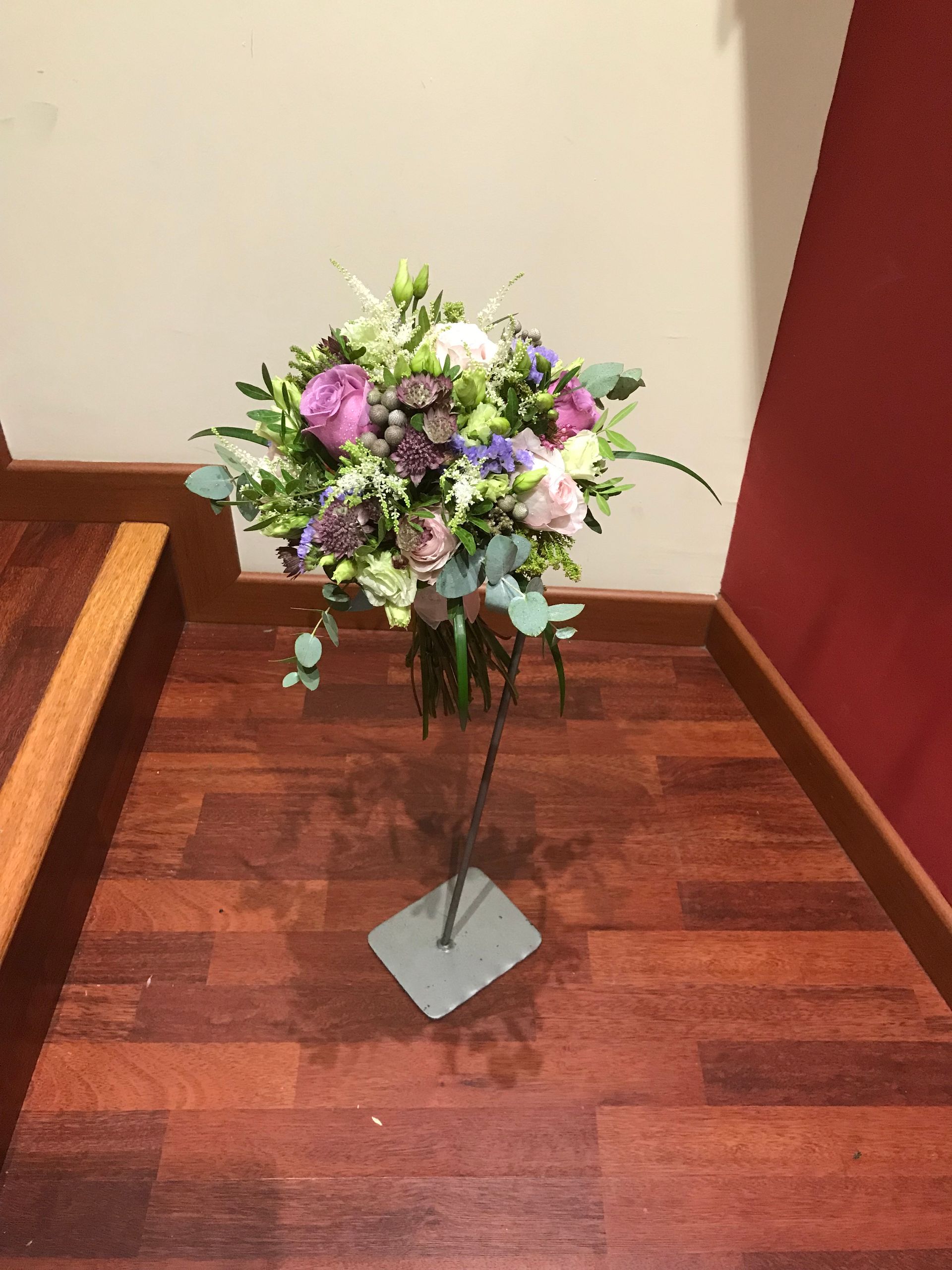 Un jarrón lleno de flores está sobre un suelo de madera.