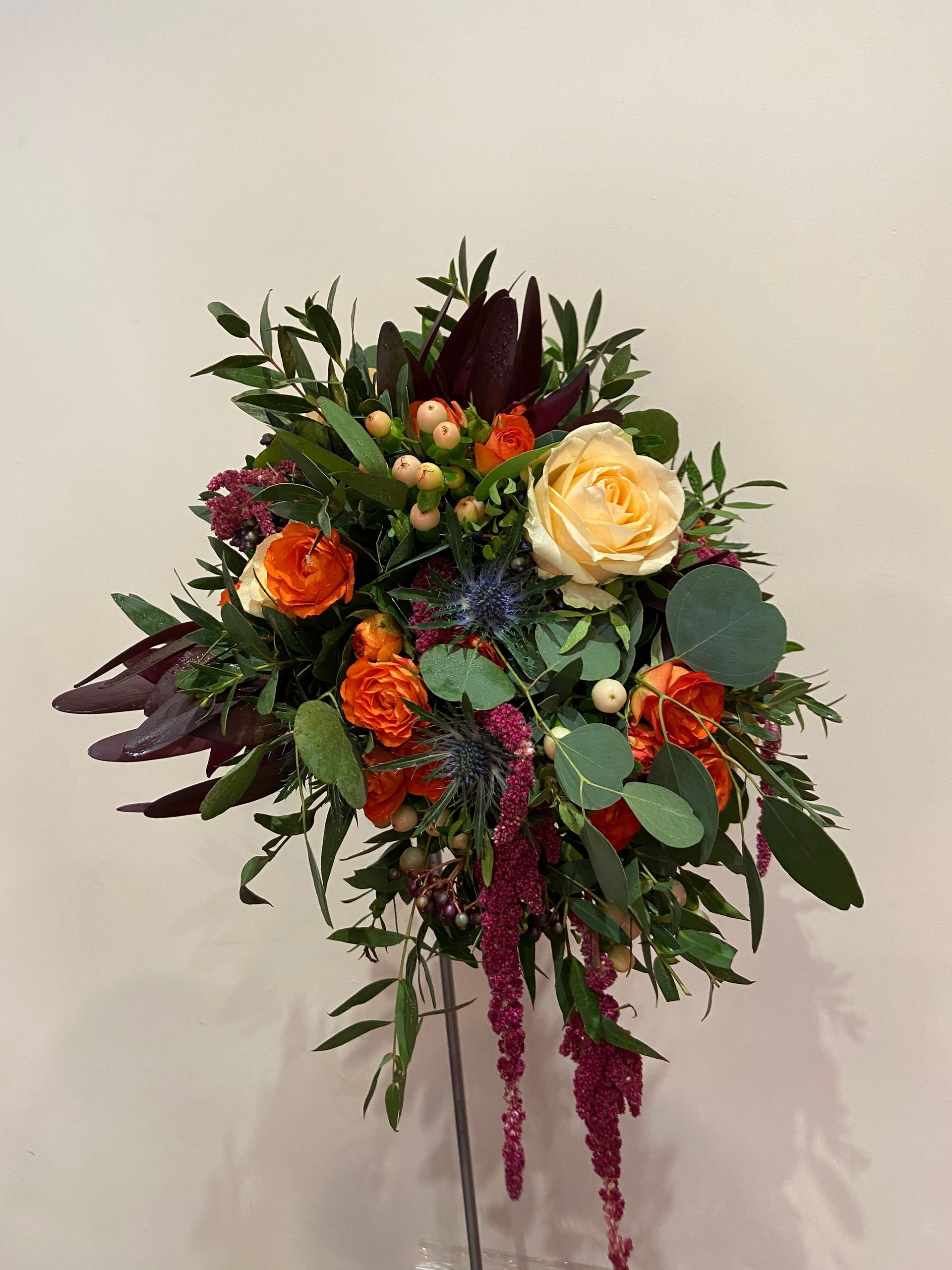 Un ramo de flores está sobre una mesa frente a una pared blanca.