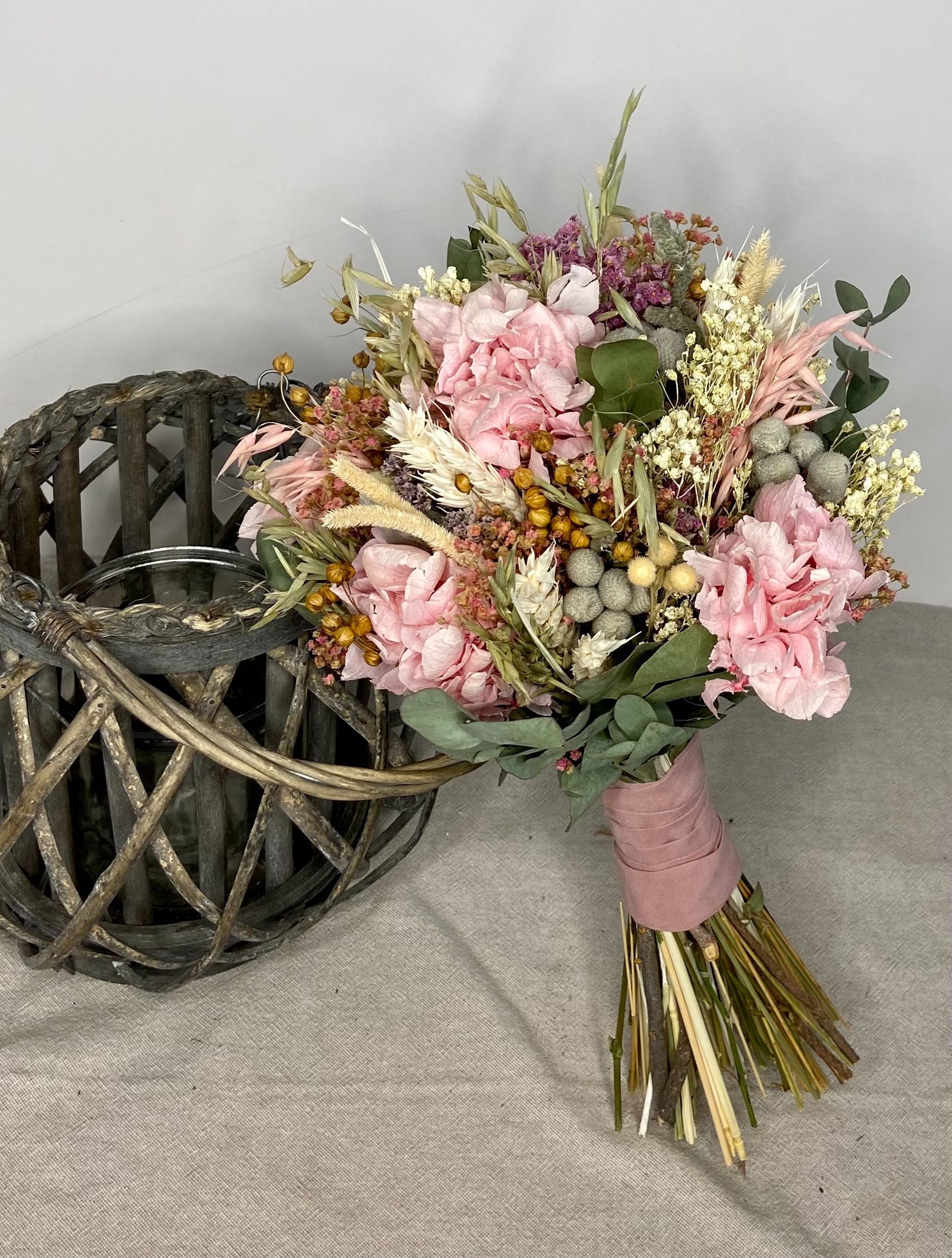 Un ramo de flores rosas está sobre una mesa al lado de una canasta.