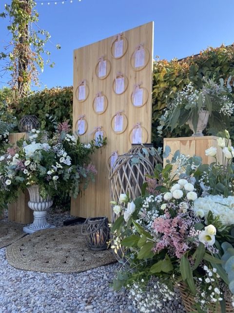 Una pared de madera con círculos está rodeada de flores.