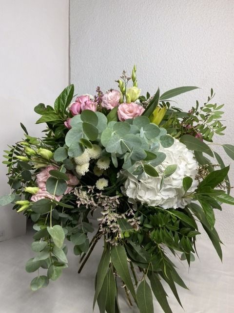 Un ramo de flores rosas y blancas con hojas verdes.