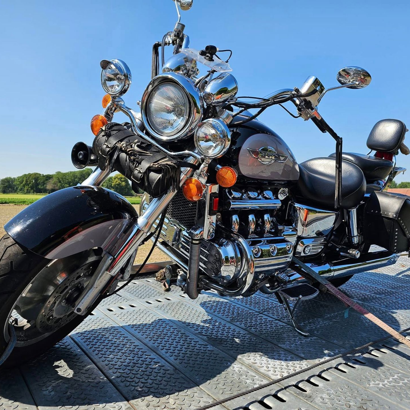 Moto noire et chromée sur une rampe, garée sous un ciel bleu.