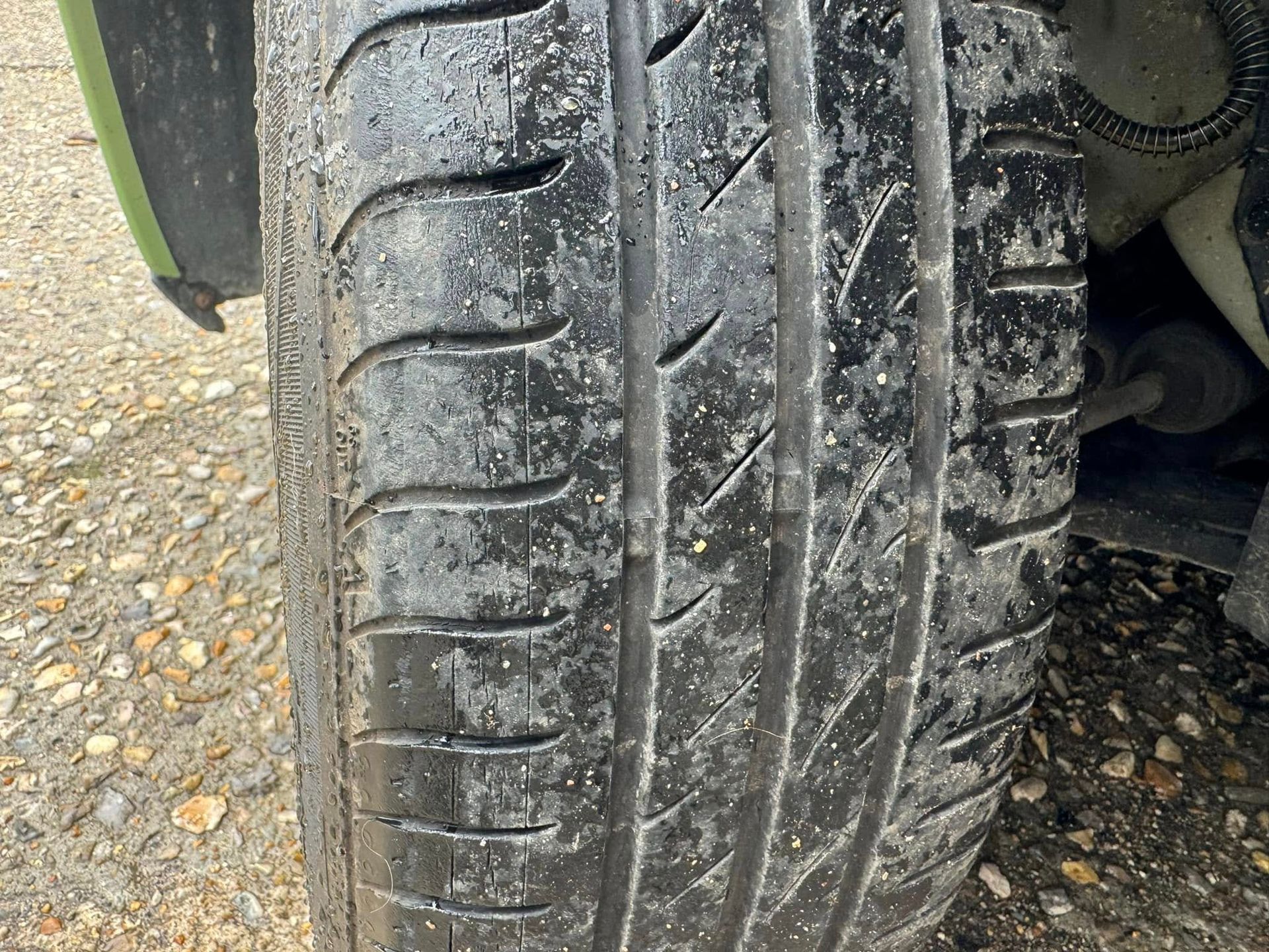 Gros plan sur un pneu de voiture à la bande de roulement usée sur une surface en béton. Vers page crevaison.