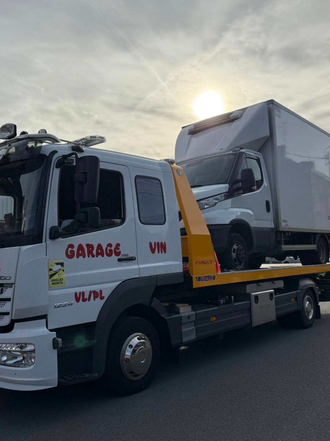 Une dépanneuse blanche transporte un fourgon poids lourds