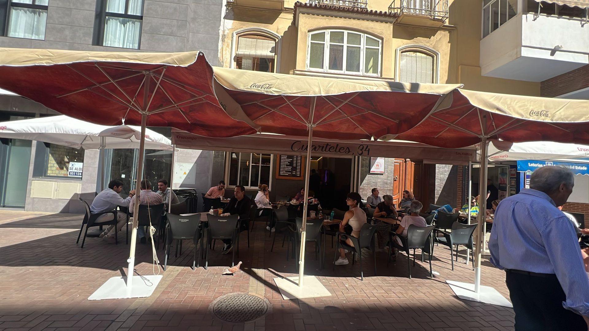 Un grupo de personas están sentadas bajo sombrillas afuera de un restaurante.