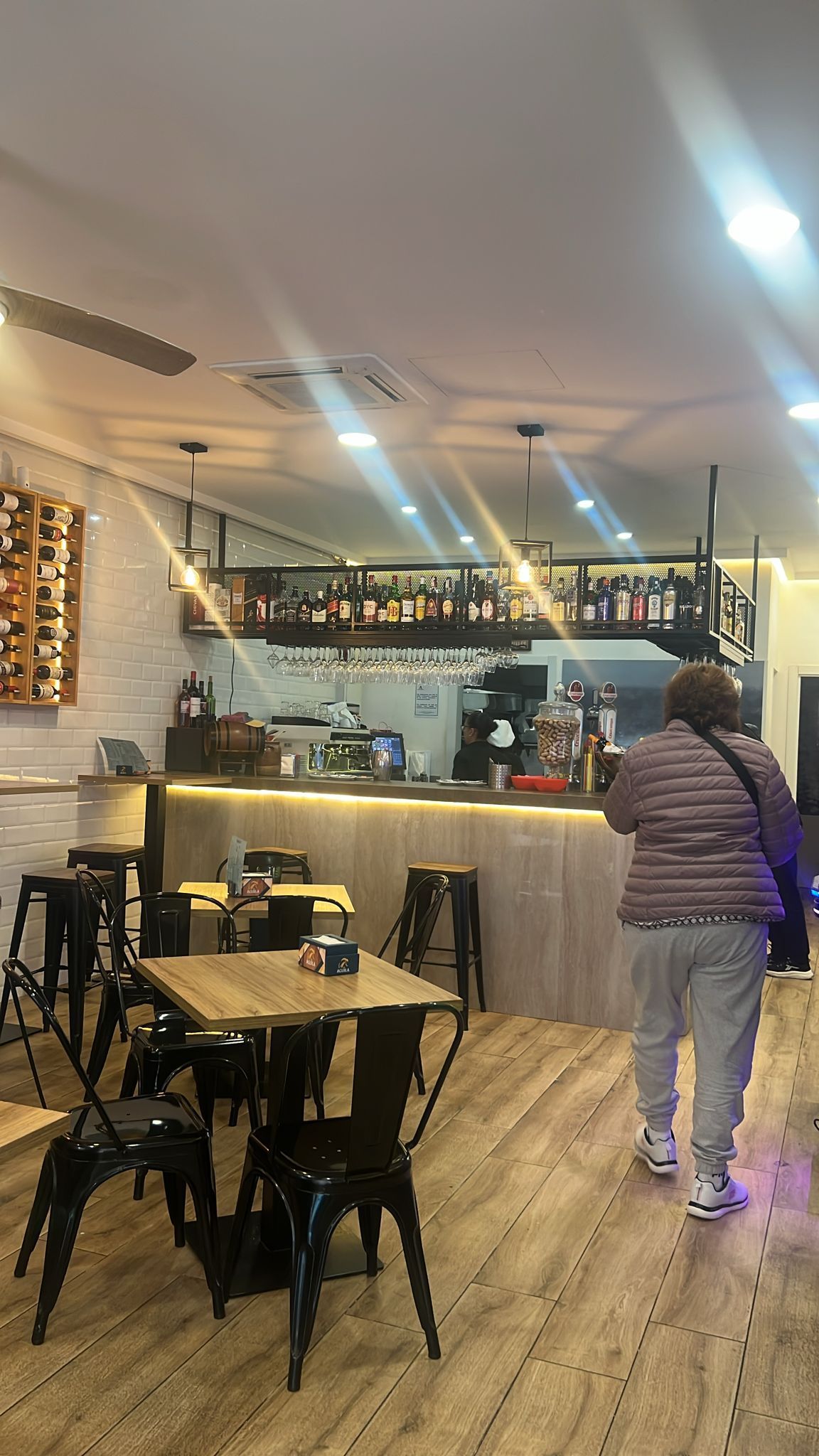 Una mujer está tomando una fotografía de un restaurante con mesas y sillas.