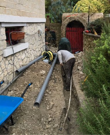 Un plombier remplace une canalisation dans un jardin