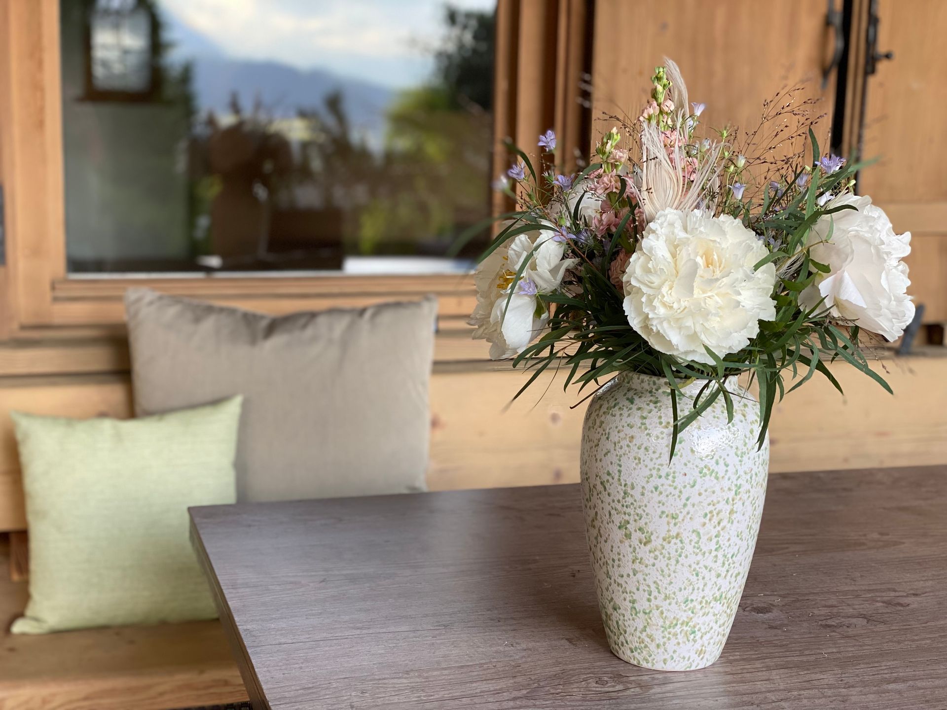 Gemütliche Sitzecke aus Holz mit Blumenstrauß auf der Terrasse des Ferienhauses Eichenseer in Gallzein, Tirol