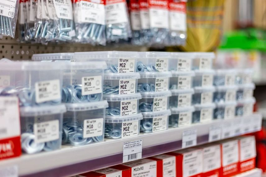 Des étagères remplies de peintures ou de fournitures de quincaillerie assorties dans une allée de magasin, les articles en boîte étant soigneusement empilés.