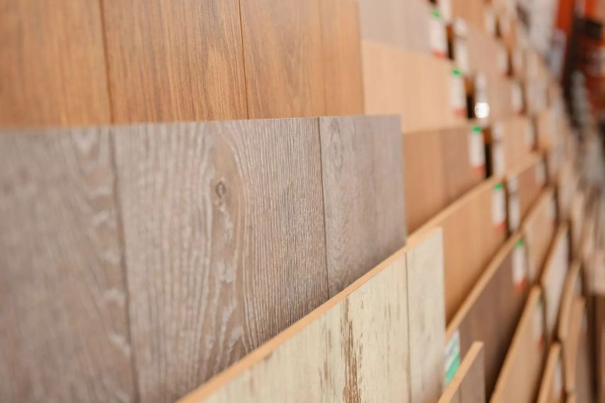 Des échantillons de lames de parquet en bois, aux finitions brunes et beiges, sont exposés dans une salle d'exposition.