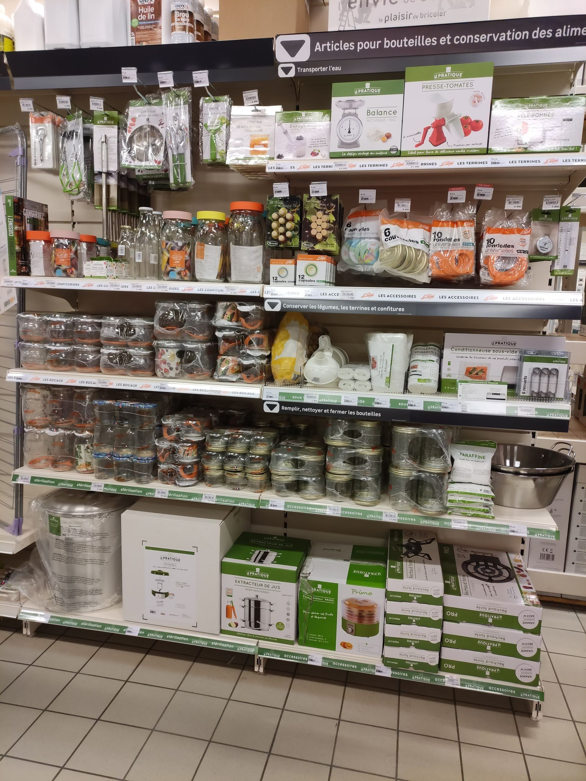 Des étagères dans un rayon de magasin regorgent de produits emballés et de bocaux assortis, dans des emballages verts et blancs.