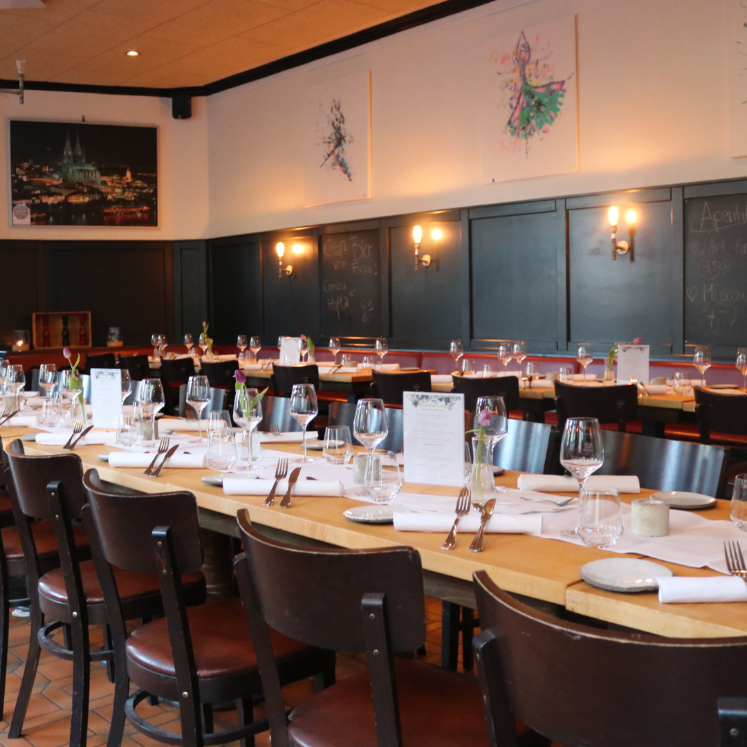 Ein langer Tisch mit einer rot-weiß karierten Tischdecke und roten Stühlen.