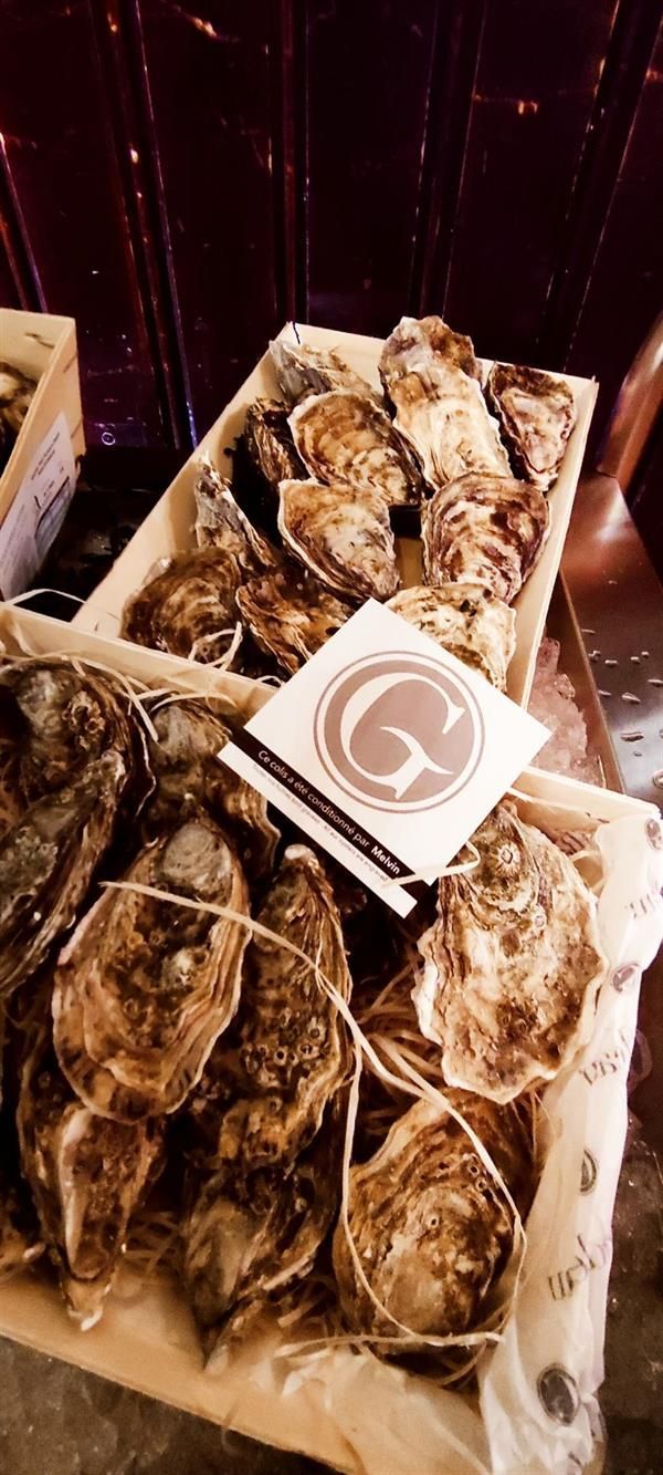 Eine Holzkiste gefüllt mit Austern und einer Karte mit dem Buchstaben G darauf.