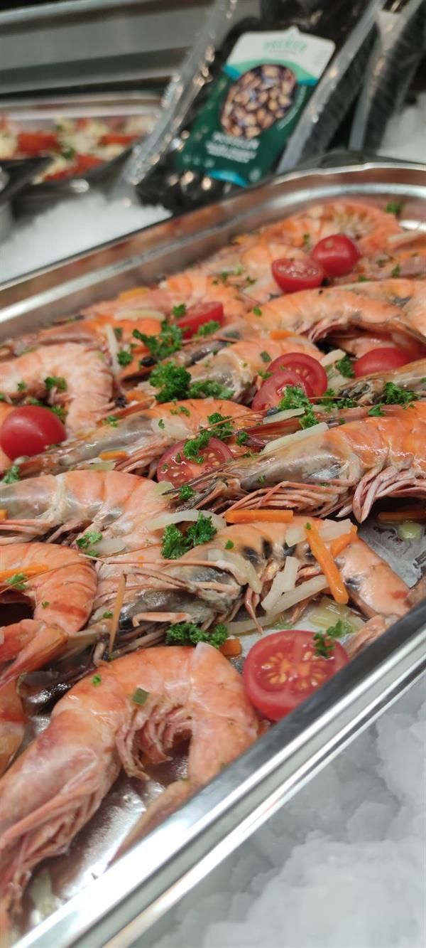 Ein Tablett mit Garnelen, Tomaten und Petersilie auf einem Tisch.