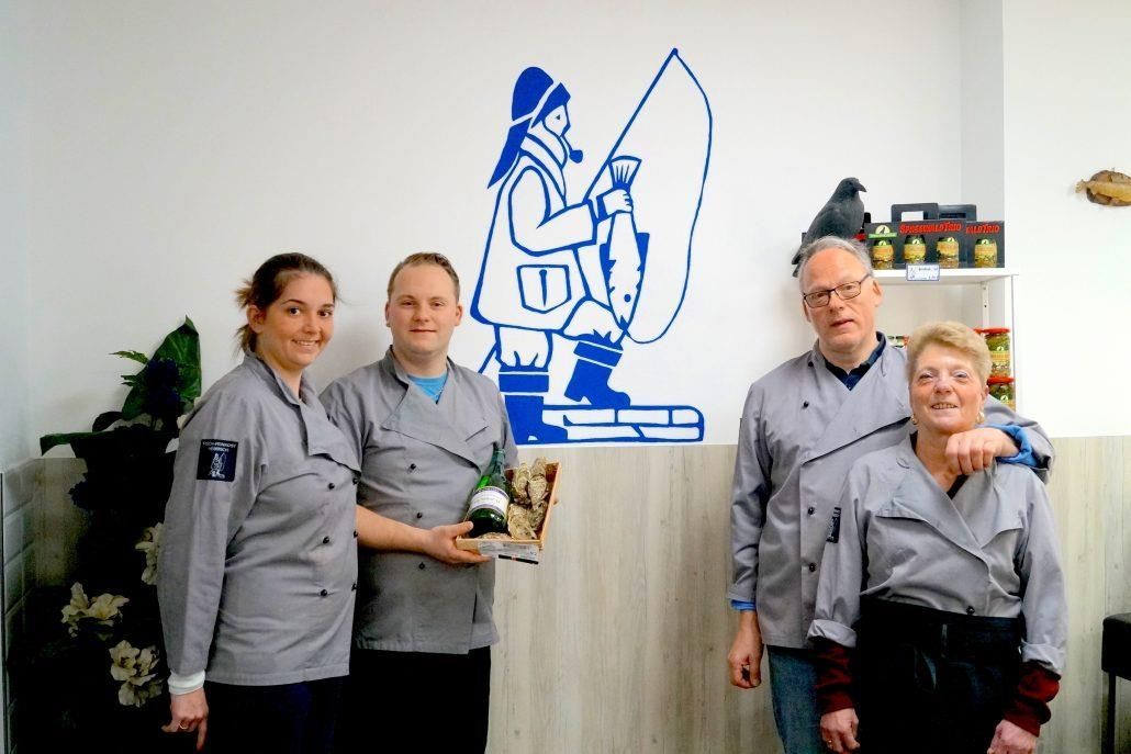 Eine Gruppe von Menschen steht vor einer Mauer mit einem Fischer darauf