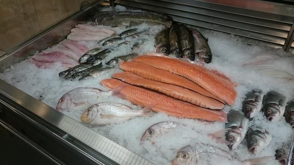 In einem Kühlschrank werden verschiedene Fische auf Eis präsentiert.