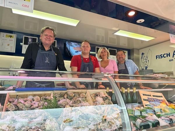 Eine Gruppe von Menschen steht vor einer Vitrine mit Meeresfrüchten.