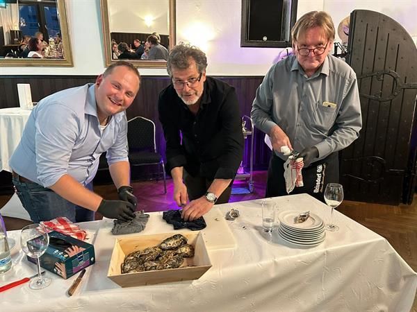 Drei Männer stehen um einen Tisch herum , auf dem eine Schachtel mit Essen steht.