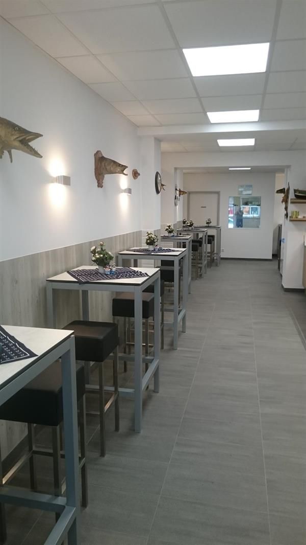 Ein langer Flur mit Tischen und Stühlen in einem Restaurant.