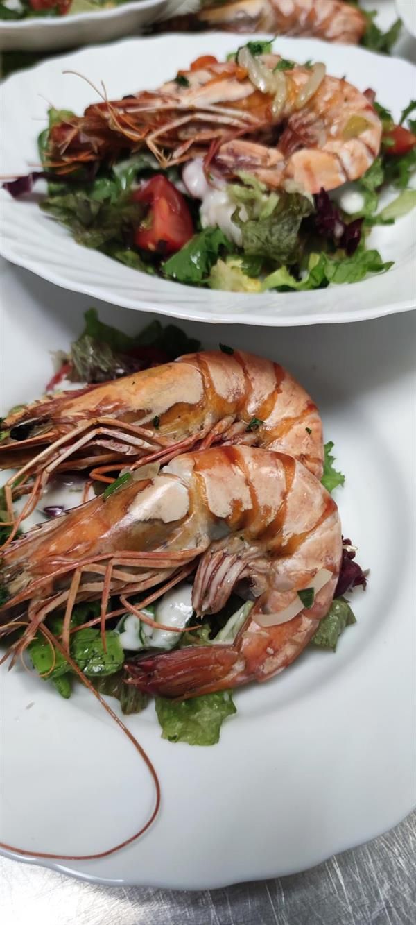 Ein Teller mit Garnelen und Salat auf einem Tisch.