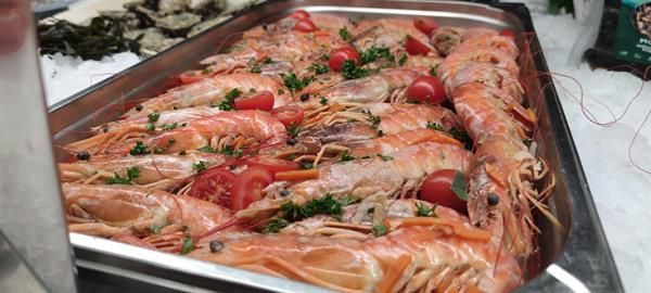 Ein Tablett mit Garnelen, Tomaten und Petersilie auf einem Tisch.