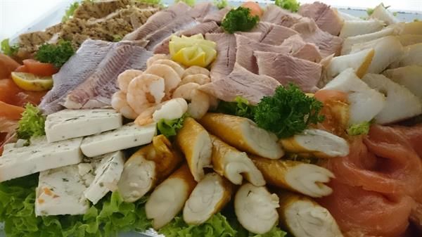 Ein Teller mit Fleisch, Garnelen, Käse und Salat auf einem Tisch.