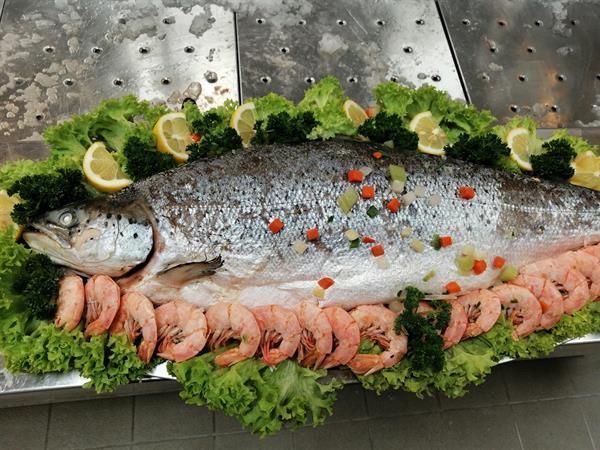 Ein großer Fisch ist von Garnelen und Salat umgeben