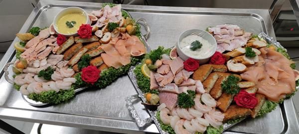 Zwei Tabletts mit Essen stehen auf einem Metalltablett auf einem Tisch.