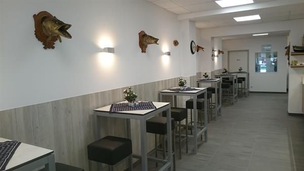 Ein Restaurant mit Tischen und Stühlen und einem Fischkopf an der Wand.