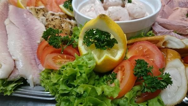 Ein Tablett mit Essen, Salat, Tomaten, Zitronen und anderem Gemüse auf einem Tisch.