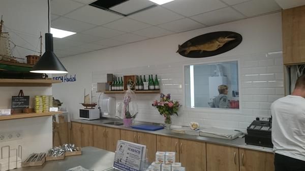 Ein Mann steht in einer Küche mit einem Fisch an der Wand.